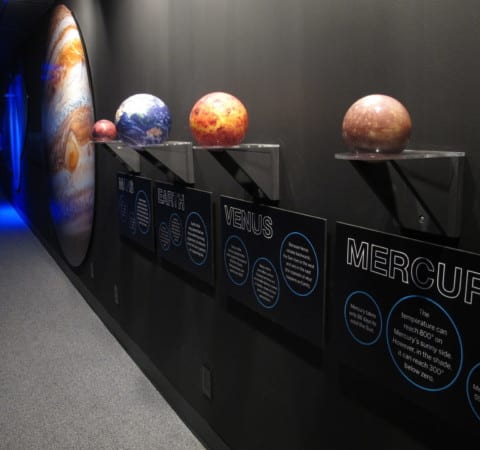 Solar system exhibit with custom fabricated planets, wall mounted display stands and educational graphics on sintra board