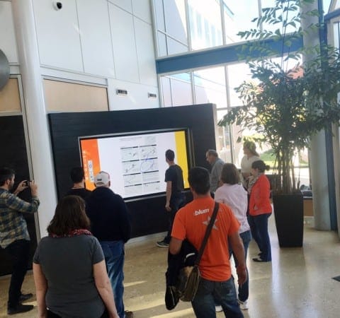 Blum visitors interact with large multi-touch digital screen with custom fabricated housing installed by Holt Environments