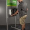 Customer using freestanding branded hygiene station with hand sanitizer and wipes